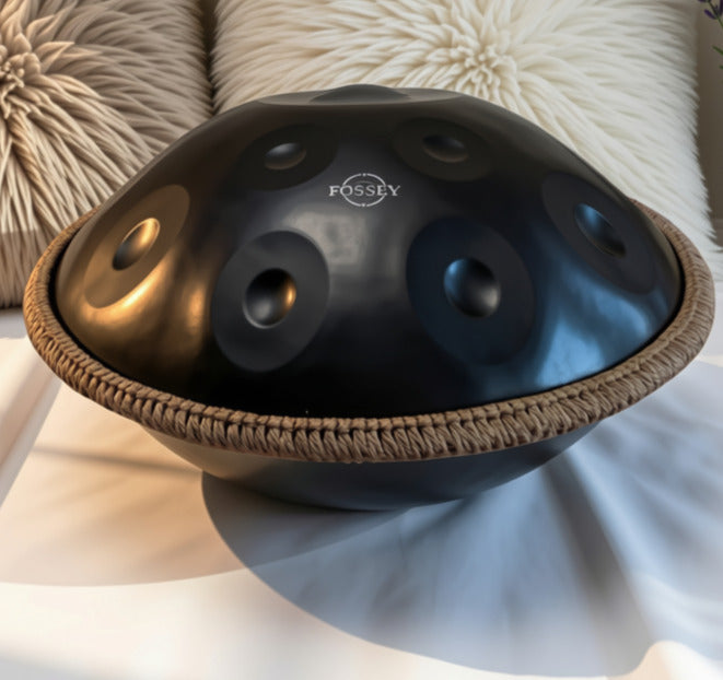 Black Fossey handpan resting on white bedding