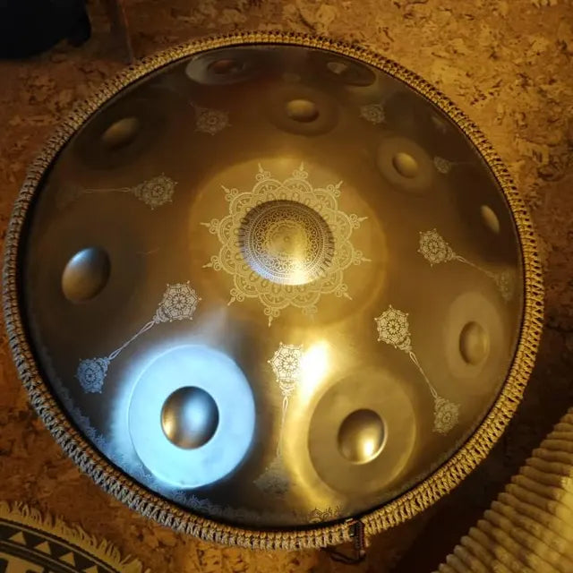 Gold-toned handpan with engraved mandala patterns viewed from above