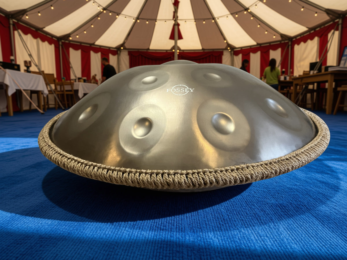 Low-angle view of a Fossey handpan inside a striped tent