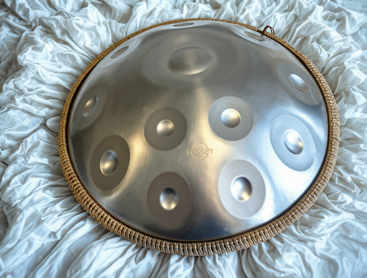 Silver-toned Fossey handpan resting on gathered white fabric