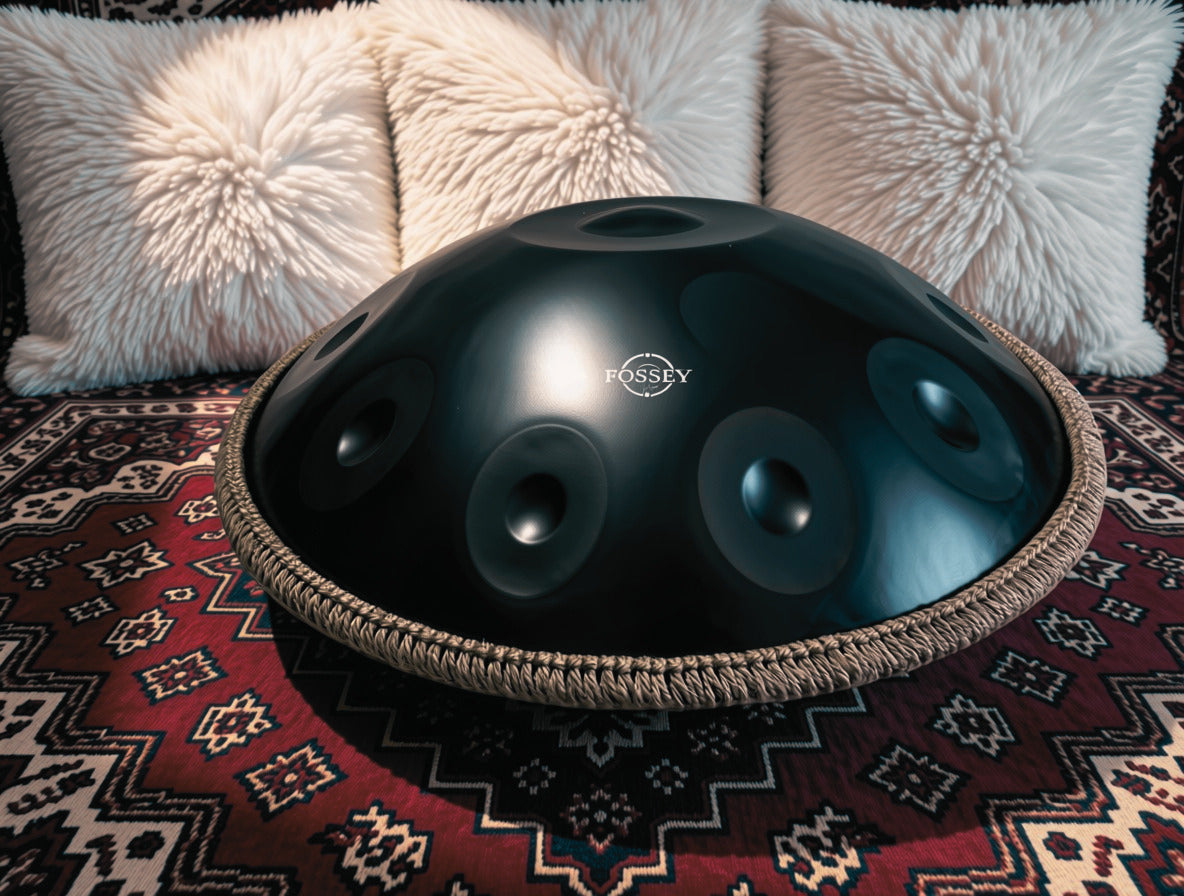 Black Fossey handpan on a patterned rug in front of white cushions
