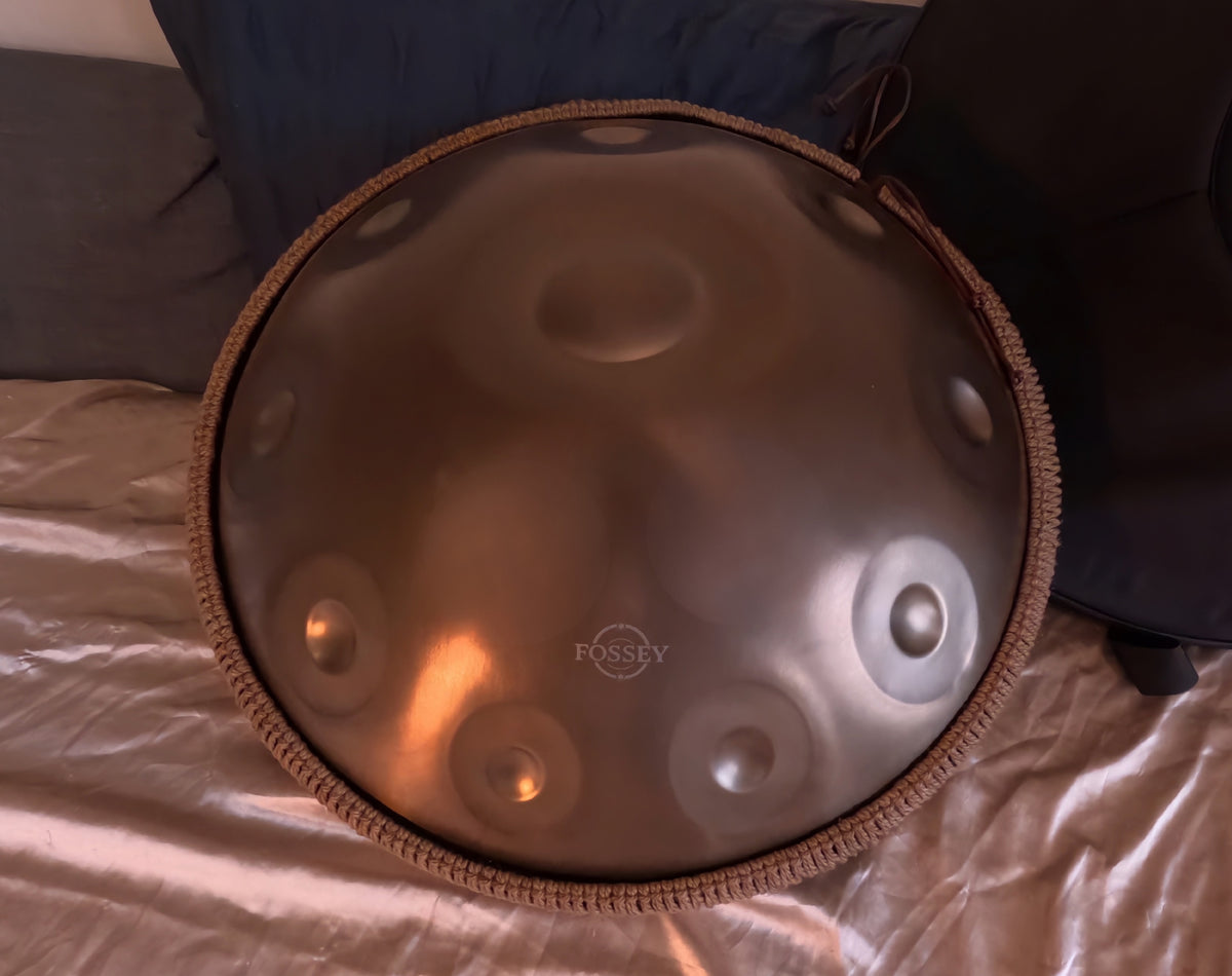 Fossey handpan propped upright against dark cushions