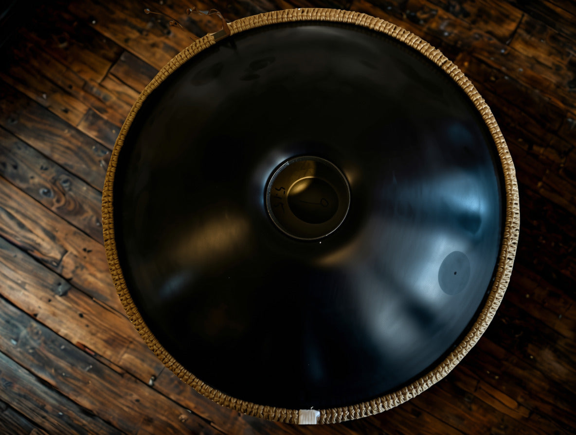 Underside of a black handpan showing the sound hole on wooden boards