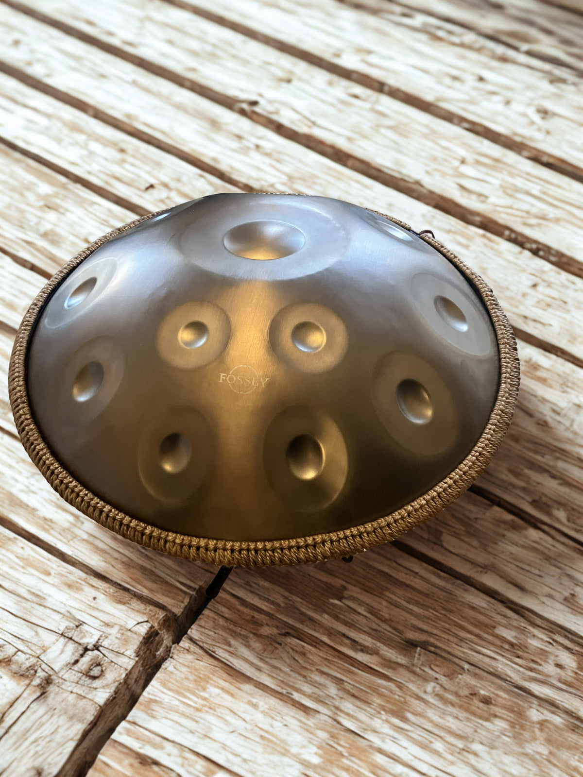 Gold-toned Fossey handpan on weathered wooden boards