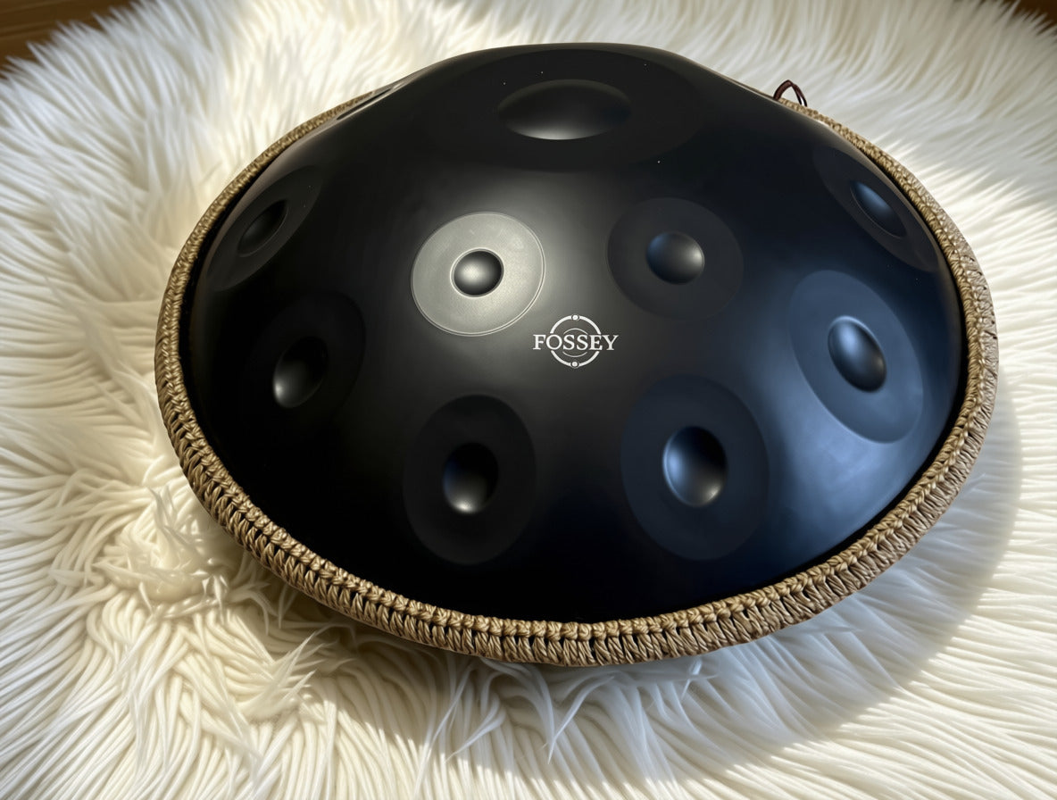 Black Fossey handpan with braided rim on white textured fabrHz 22' Stainless Steel 1.1 thick, Hand-Tuned ... Fossey Handpan