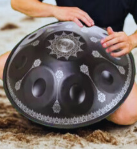Person playing a dark handpan with engraved mandala decoration. Black Yantra Fossey Handpan, D Kurd,22" Stainless Steel - 10 notes