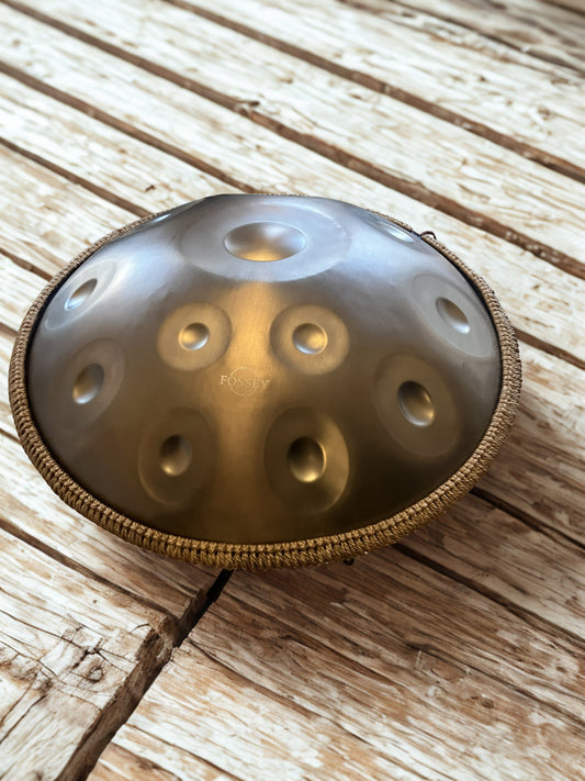 Gold-toned Fossey handpan on weathered wooden boards