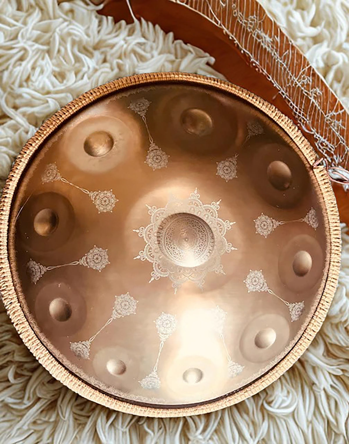Gold Yantra handpan with engraved mandalas beside a stringed instrument on a white rug. Gold Yantra design 10 notes Handpan D Kurd 432 Hz 22' Stainless Steel, Hand-Tuned