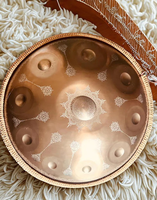 Gold Yantra handpan with engraved mandalas beside a stringed instrument on a white rug. Gold Yantra design 10 notes Handpan D Kurd 432 Hz 22' Stainless Steel, Hand-Tuned