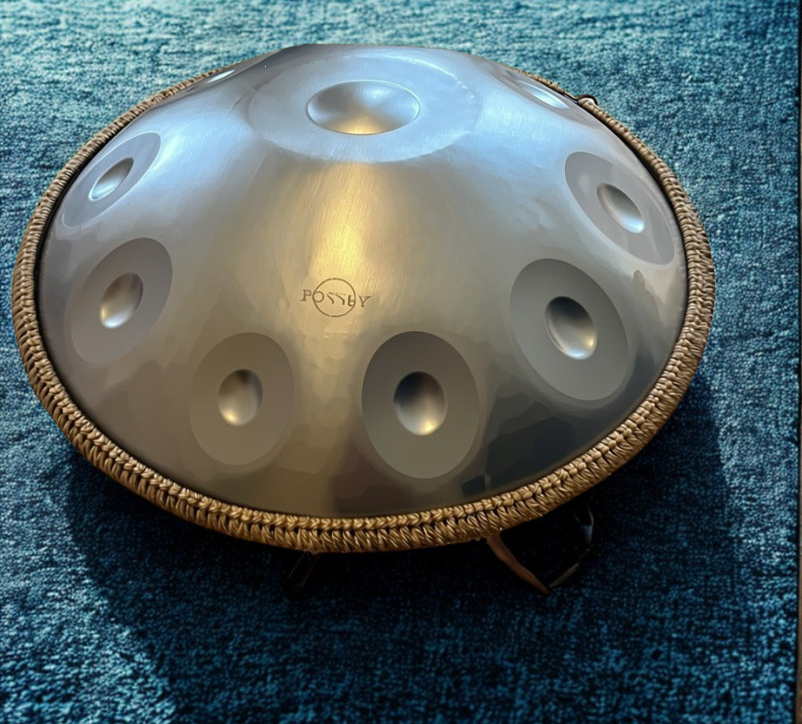 Silver-toned Fossey handpan on a blue rug. Silver Shine Fossey Handpan - 10-Note, 432hz, D Kurd, Stainless Steel