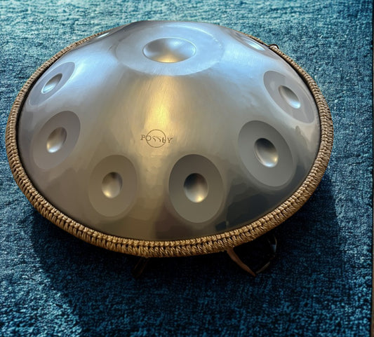 Silver-toned Fossey handpan on a blue rug. Silver Shine Fossey Handpan - 10-Note, 432hz, D Kurd, Stainless Steel