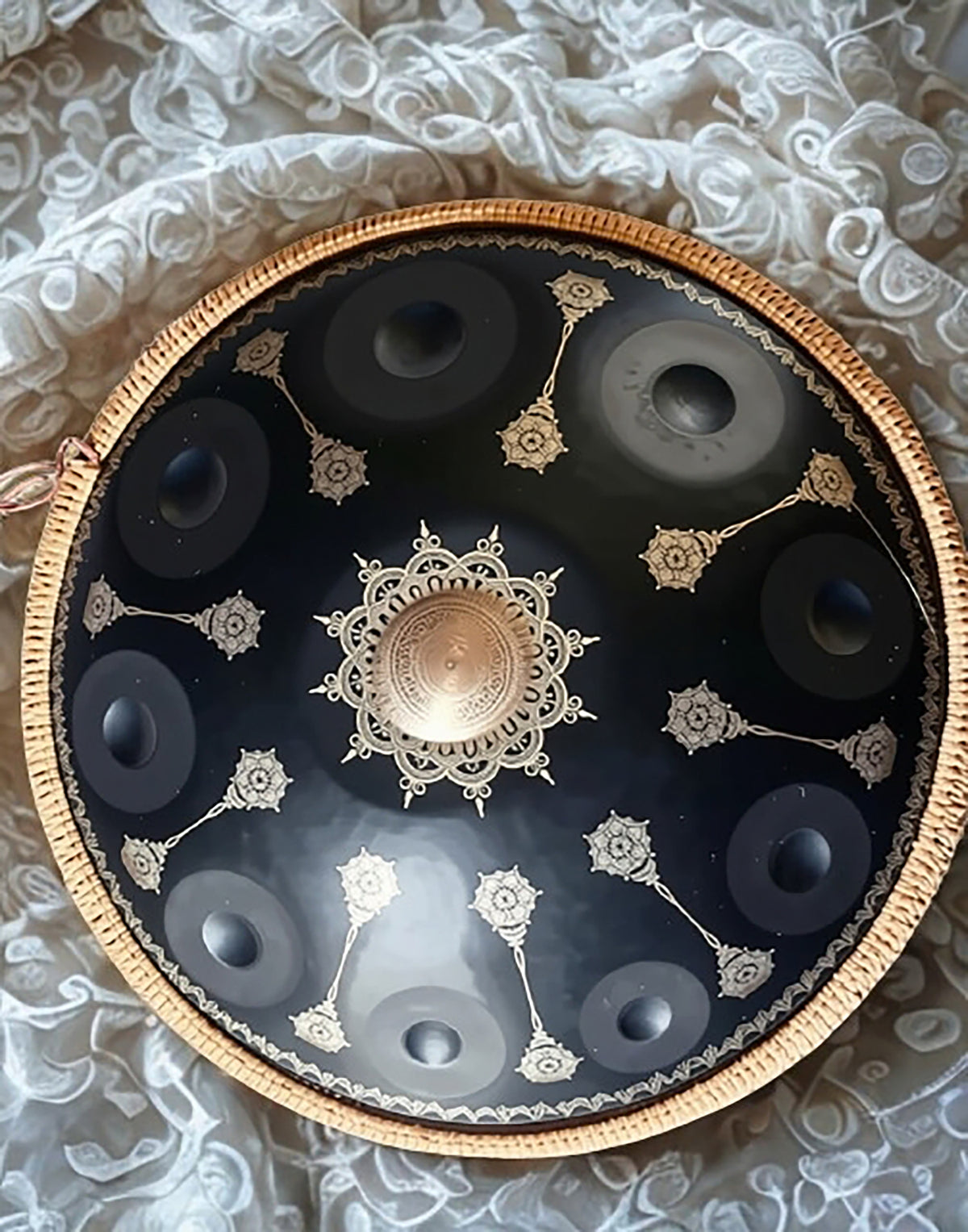 Black Yantra handpan with gold mandala engravings on white lace fabric